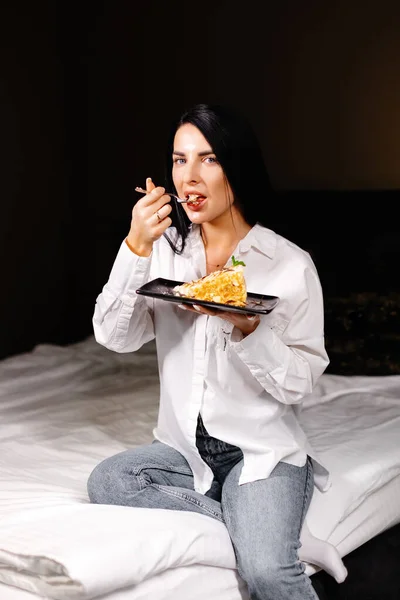 Gülümseyen Esmer Kadın Dairesindeki Yatak Odasında Pasta Yiyor — Stok fotoğraf