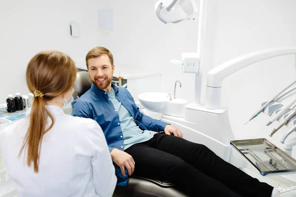 Blond Kvinnlig Tandläkare Tandläkarmottagningen Talar Med Manlig Patient Och Förbereder — Stockfoto