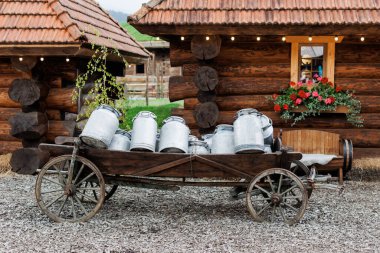 Köydeki ahşap evlerin yakınındaki ürünleri teslim etmek için uzun zaman önce çiftçiden bir sürü alüminyum teneke kutu taşıyan eski ahşap bir araba kullanılmış....