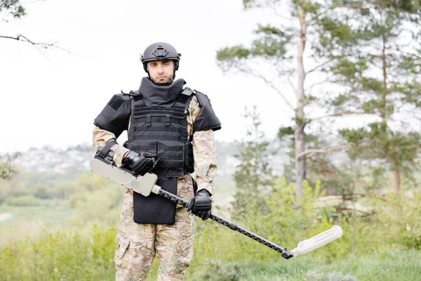 Un hombre con un uniforme militar y un chaleco antibalas se sienta
