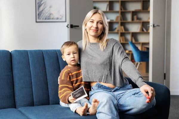 Young Pregnant Woman Her Son Sit Sofa Home Boy Holds — Fotografia de Stock