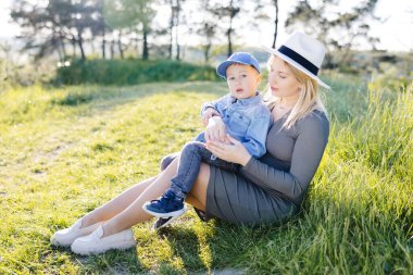 Hamile anne ve küçük oğlu ormanda yürüyüp sarılıyorlar ve birlikte eğlenceli vakit geçiriyorlar.