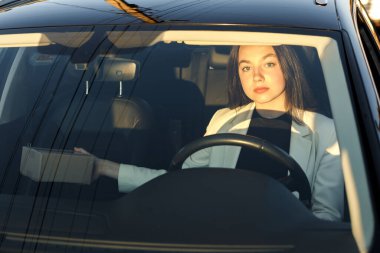 Genç ve mutlu bir iş kadını araba sürerken bir paket alıyor, arabanın penceresinden bakıyor..