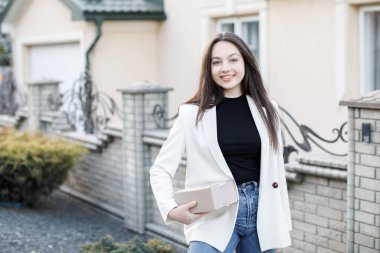 Young woman carrying parcels home, standing with a heap of cardboard boxes.