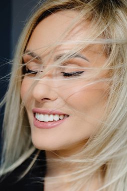 Şehirdeki gri duvarda dalgalı saçları olan güzel, şık bir kadının portresi..