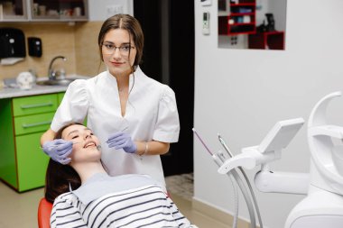 Kadın dişçi, genç bayan hasta için tedavi görüyor, diş aletleri tutuyor, lastik eldiven takıyor. Modern diş sağlığı kliniği kavramı.