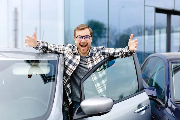 站在汽车旁快乐的家伙 把大拇指抬起来在经销商中心购买汽车 — 图库照片