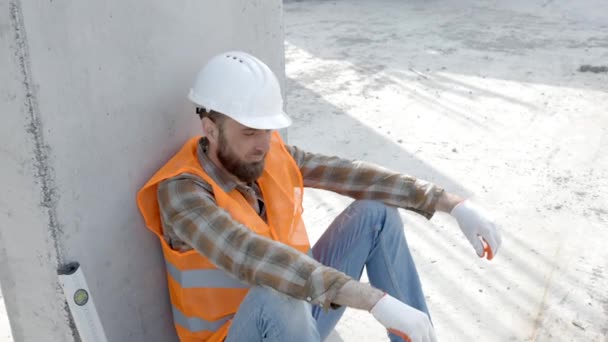 建筑工人 戴安全帽的工头和背心的工头坐在工具箱和尺子旁边的工作场所休息 — 图库视频影像