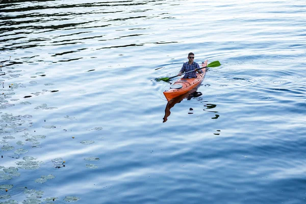 在河里划船 一个年轻的白人男子坐在皮划艇上划桨 水娱乐的概念 — 图库照片