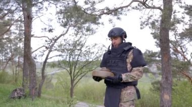 Özel takım elbiseli bir adam dedektörle çalışıyor ve patlayıcı bir cihaz buldu. Adamın biri tanksavar mayınını etkisiz hale getirmeye çalışıyor.