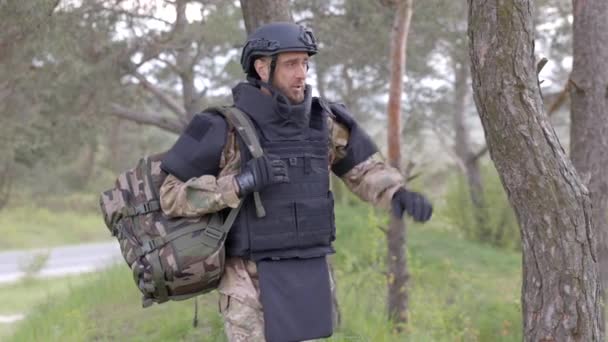 身穿制服和战术背心的年轻士兵在森林里工作 准备在一个临时的森林基地采取行动 一名男子在该地区从事排雷工作 — 图库视频影像