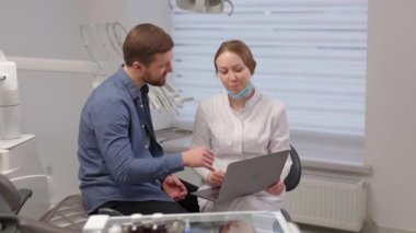 Yakışıklı genç bir adam dişçi randevusunda parlak, güzel bir ofiste bayan bir doktorla konuşuyor. Dişçi hastaya açıklar ve dizüstü bilgisayardaki her şeyi gösterir.