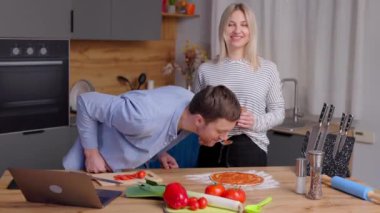 Romantik çift mutfakta yemek pişiriyor. Yakışıklı adam ve çekici genç kadın salata ve pizza yaparken birlikte eğleniyorlar. Sağlıklı yaşam tarzı kavramı.