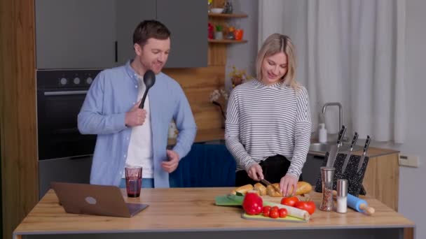 玩乐的夫妇在厨房里玩 快乐的男人用厨房用具当麦克风 女人切面包当晚餐 — 图库视频影像