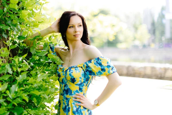 stock image Young woman in summer dress is walking in green park and enjoying the sun. Playful and beautiful girl on warm sunny day