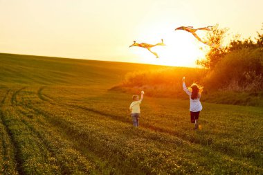 Mutlu çocuklar gün batımında sahaya uçurtma fırlatırlar. Küçük oğlan ve kız yaz tatilinde..