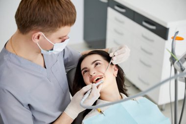 Diş hekimliğinde dişçi sandalyesinde gülümseyen bir kızın portresi.