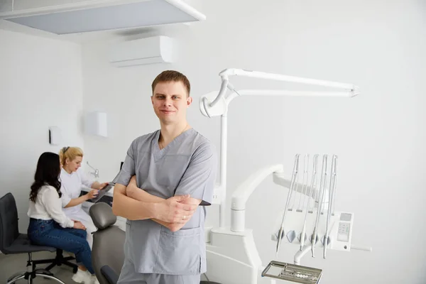 Jovem Dentista Está Meio Consultório Fundo Colega Está Aconselhando Pacientes — Fotografia de Stock
