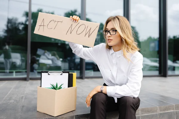 物の箱の隣にポスター法で屋外に座っている女性 失業に対するストライキで美しい女性抗議者 — ストック写真
