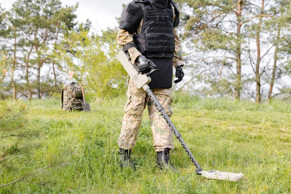 Un hombre con uniforme militar y un chaleco antibalas se sienta en
