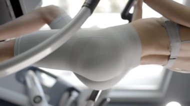 Spor giyim bölümünde spor salonunda çalışan genç bir kadın. Merdiven simülatöründe çalışıyor.