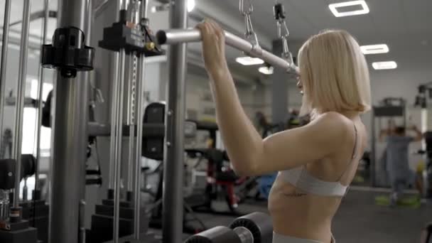 Sportig Kvinna Grå Kostym Drog Sportsimulator Gymmet Ryggmusklerna Mycket Spända — Stockvideo