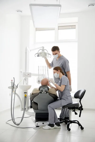 医院两名医生身着医服 检查病人的口腔 分析牙齿健康状况 为口腔外科手术作准备 在正畸诊所工作的口腔科医生 — 图库照片