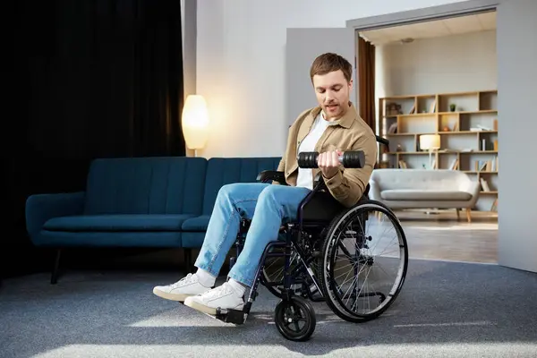 Physical rehabilitation for disabled people. Happy guy in wheelchair making exercises with dumbbell at home. Cheerful impaired young man working out with weights indoors.