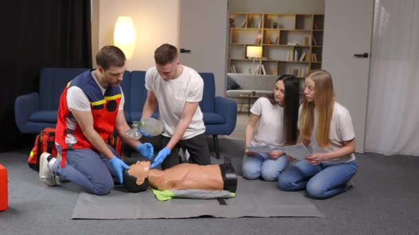 被害者への応急処置 グループでの基本的な緊急訓練 マネキンに人工肺換気を示す男 間接的な心臓マッサージ — ストック動画