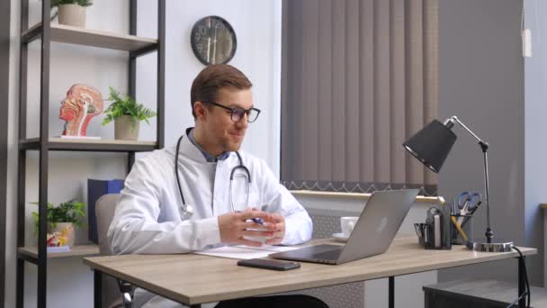 医生坐在他工作的地方的办公桌前 用笔记本电脑工作 完美的医疗服务在诊所 医疗和医疗保健的美好未来 — 图库视频影像