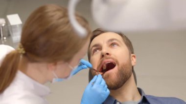 Modern klinikte dişçi koltuğunda oturup gülümseyen mutlu bir adamın portresi. Profesyonel dişçide diş tedavisinden hoşlanan hasta