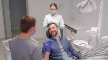 Handsome male patient looking at his beautiful smile sitting at the dental office