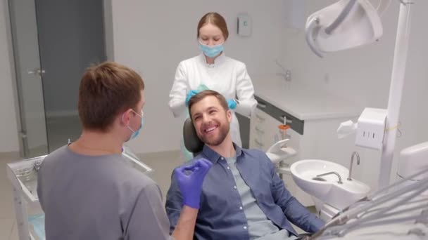 stock video Handsome male patient looking at his beautiful smile sitting at the dental office