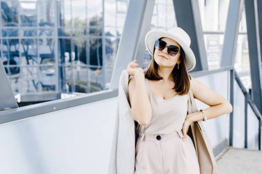 Güzel esmer iş kadını takım elbiseli, beyaz şapkalı, sokakta yürüyen. Toplantıya yürüyen güzel bir kadın.