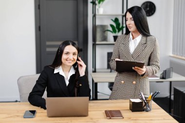 Çağrı merkezi ajanının kulaklığı modern ofiste yardım hattında çalışıyor. Ofiste iki çekici kadın çalışıyor..