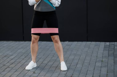 Esnek lastik direnç bantlı kadın eğitimi şehrin dışında, arka planda, karanlık duvarda.