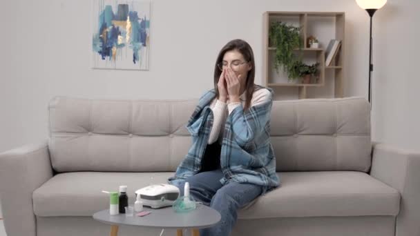 カジュアルな服を着た若い女性は 鼻スプレーを使用して呼吸を促進し 家庭内でソファーに座って — ストック動画