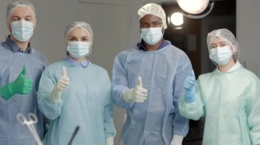 Ameliyat sonrası ameliyat odasında maskeli bir grup doktor el kol hareketi yapıyor.