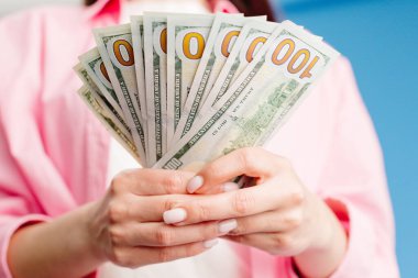 Yüz dolarlık banknotların mavi arka plan destelerini sayan kadın elleri yakın plan. Amerikan parası, dolar.