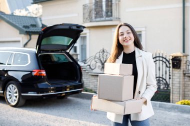 Genç bir iş kadını bir araba bagajından paketler alıyor, arabayla eve geliyor..