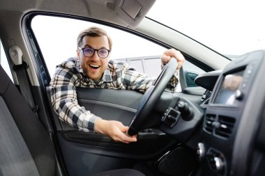 Genç adam yeni arabasının camından bakıyor, modern galeriden almadan önce kontrol ediyor. Galeride araba alan ya da kiralayan neşeli adam..