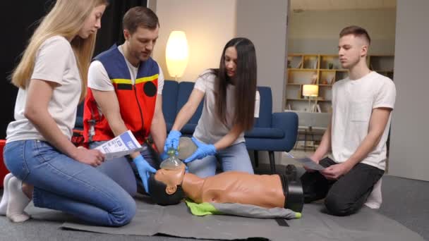 屋内トレーニング中にダミーと応急処置の心臓圧縮を行う方法を学ぶ人々のグループ — ストック動画