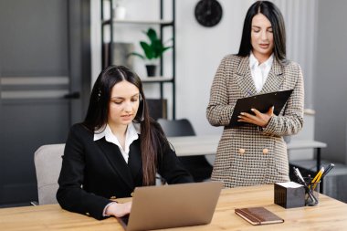 Çağrı merkezi ajanının kulaklığı modern ofiste yardım hattında çalışıyor. Ofiste iki çekici kadın çalışıyor..