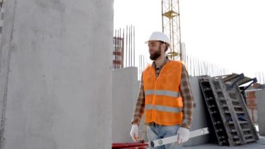 İnşaatçı, miğfer ve yelek giyen ustabaşı inşaat halindeki bir binada iş yerinde çalışıyor.