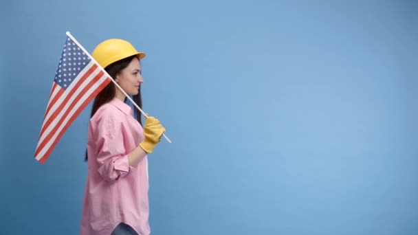 Девушка Строительном Шлеме Перчатках Американским Флагом Стоит Синем Фоне — стоковое видео