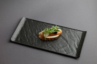 Somonlu bruschetta. Krem peynirli somon tostu, roka ve koyu zeytinli..