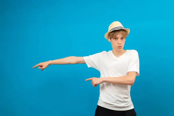 stock image Young teen man points palms aside isolated on blue. Friendly well-looking boy paying your attention at copy space, best deal, sale, presenting novelty