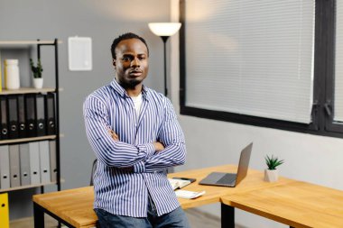 Ofisinde kollarını kavuşturmuş başarılı bir zenci..