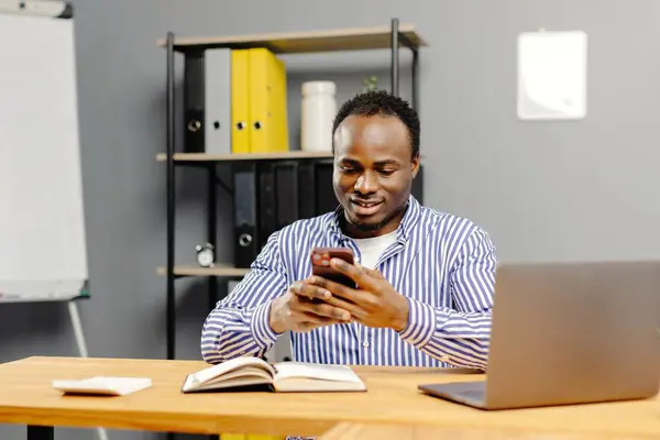 stock image Man sitting at desk using mobile phone.