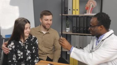 A young attractive otolaryngologist doctor gives a consultation to a female patient. A doctor explains how to wear a hearing aid to a woman